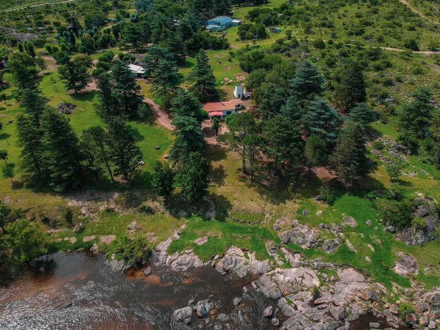 Vista aérea del campo: el río, el monte serrano y el casco arbolado