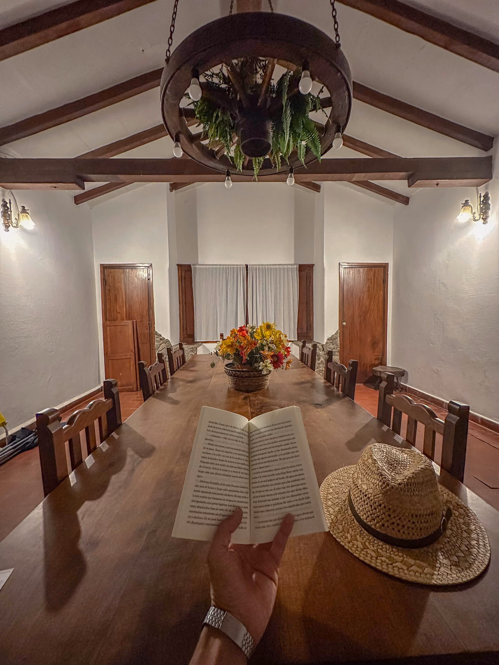 Comedor de Los Pinares, con mesa larga de madera y araña de rueda de carro